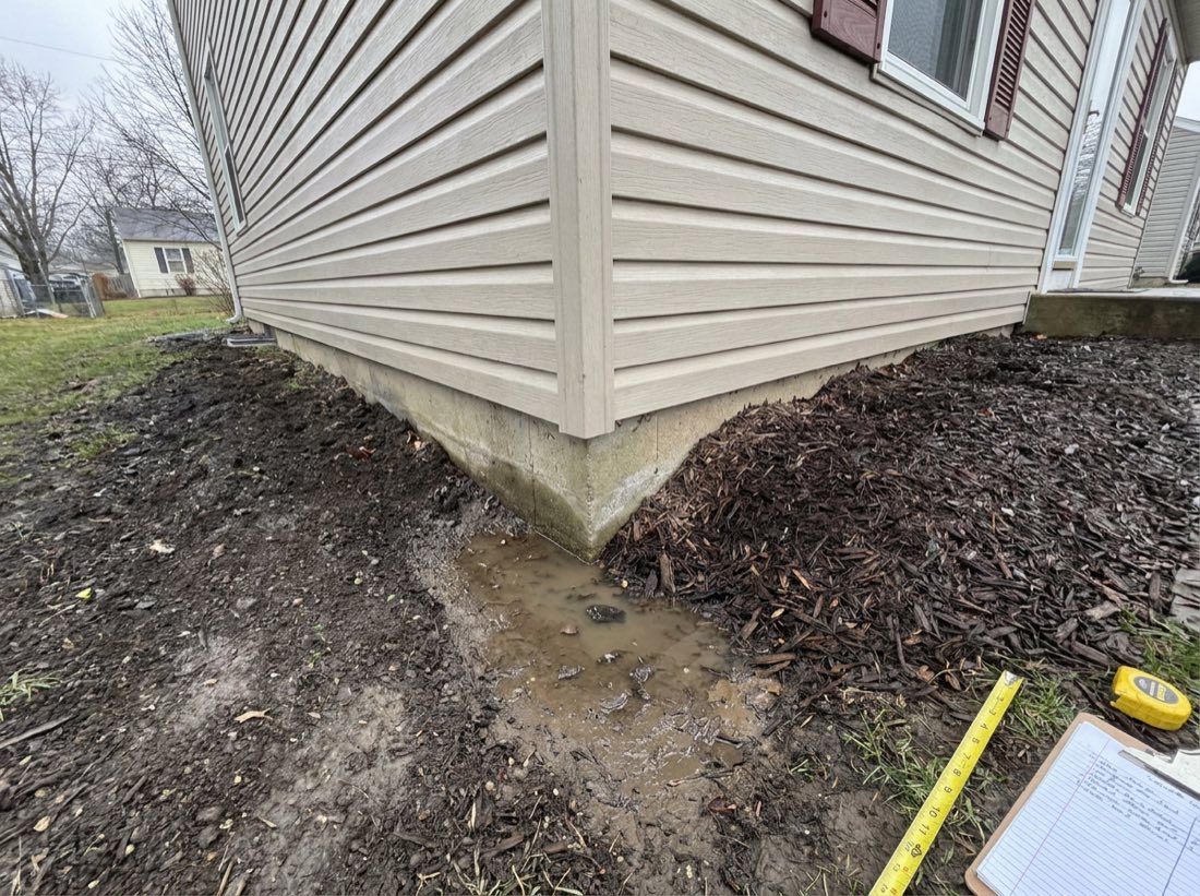 Soil graded toward the house with mulch piled against siding